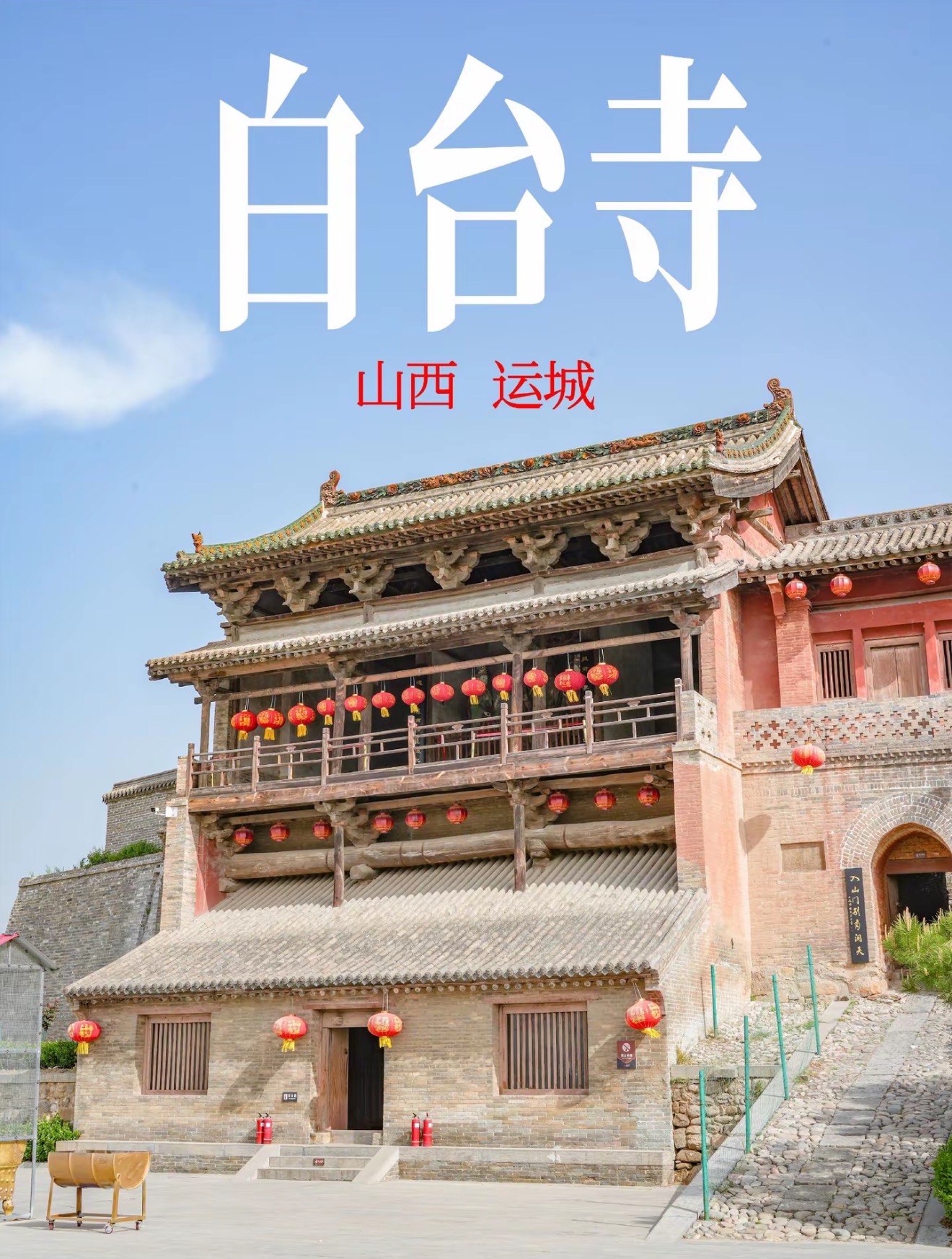白台寺古朴楼阁式建筑，檐下悬挂成排红灯笼，蓝天白云与石板广场